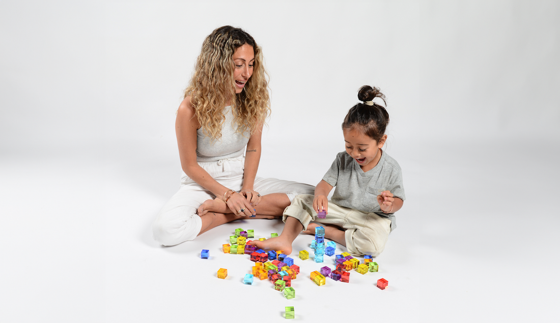 Mother and toddler playing with colourful CMY shapes on the floor